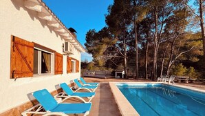 Ein Poolbereich mit Liegestühlen, einem Schwimmbecken und einem Gebäude mit Holzjalousien.