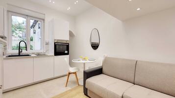 Une cuisine moderne avec des meubles blancs, une table à manger avec des chaises et un canapé.