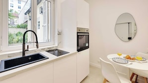 Una cocina moderna con pileta, estufa y comedor, con platos y vasos.