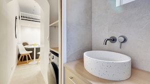 Un baño moderno con lavamanos independiente, perchero y zona de ducha.