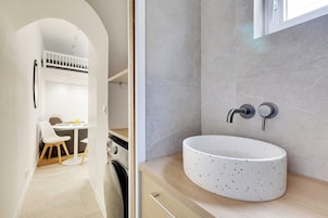 Un baño moderno con lavamanos independiente, perchero y zona de ducha.