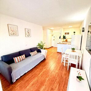 A living room with a sofa, a dining table with chairs, a kitchen area with cabinets, and a refrigerator. - Charming apartment in Minerva Building, just a short walk from the beach in Arroyo de la Miel (Arroyo de la Miel)