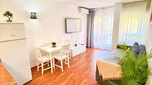 Kompakti oleskelutila, jossa on ruokailualue, sänky, televisio ja pieni keittokomero.