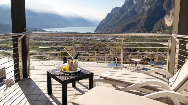 A balcony with a table, chairs, and a view of a mountainous landscape and a body of water. - Acetaia del Balsamico Trentino (Tenno)
