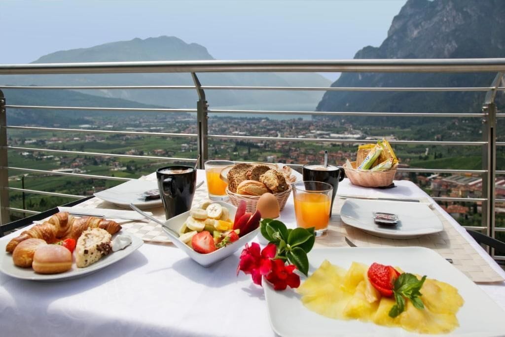 Ein Esstisch mit Croissants, Obst und Saft, mit Blick auf eine Berglandschaft.