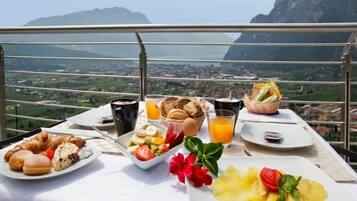 Ein Esstisch mit Croissants, Obst und Saft, mit Blick auf eine Berglandschaft.