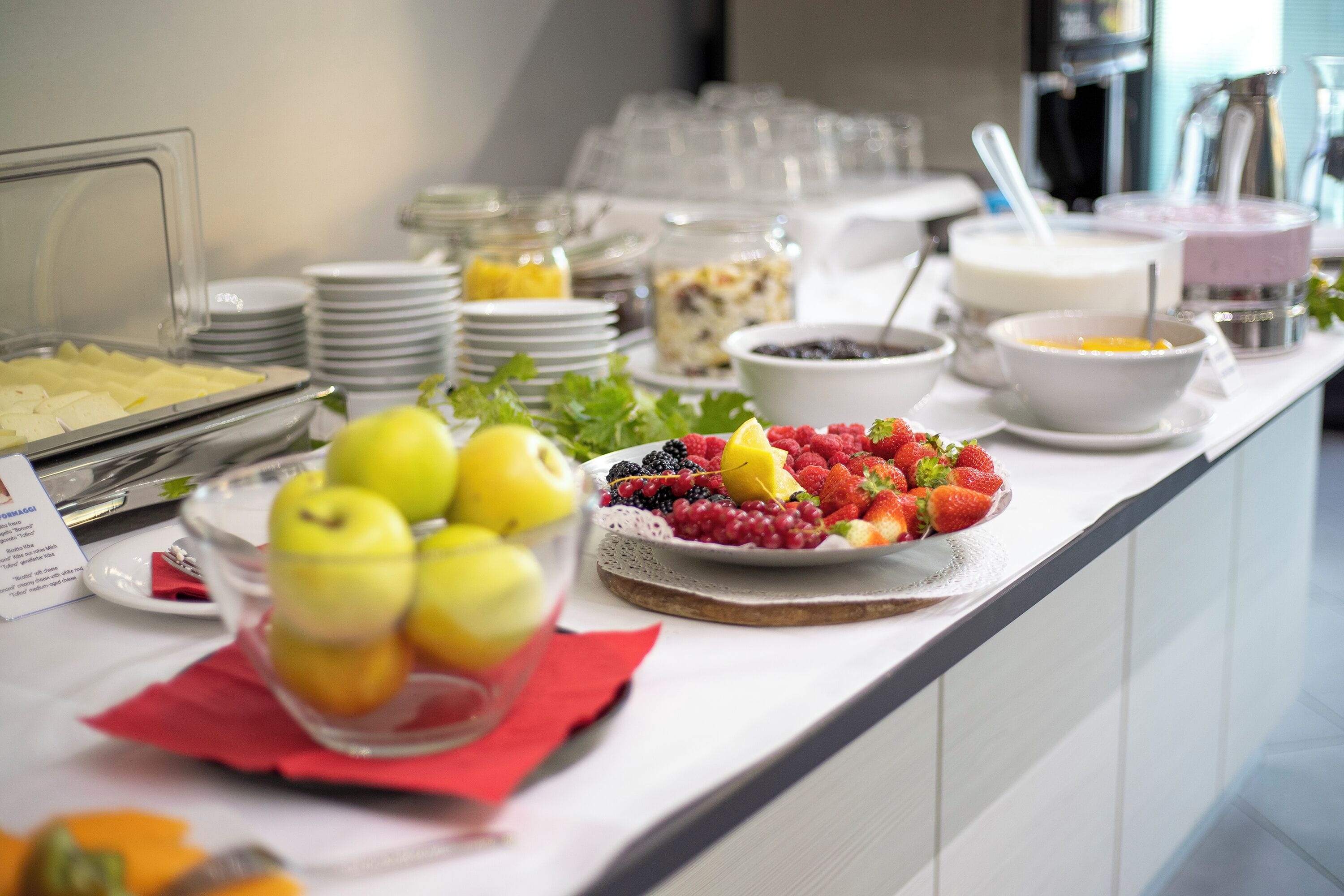 Un bufé con diversos alimentos, entre ellos frutas y tazones con distintos platos.