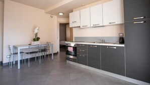 A modern kitchen with stainless steel appliances, a dining area with a table and chairs, and a small potted plant. - Acetaia del Balsamico Trentino (Tenno)