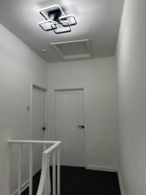A narrow hallway with white walls, a white door, and a white railing. - 2 bedroom house in central swansea (Swansea)