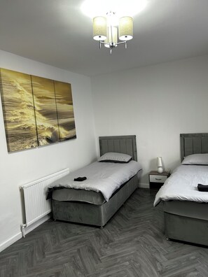 Ein Schlafzimmer mit zwei Betten, einem Nachttisch, einer Lampe und einem Wandbild.