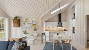 A spacious living room with a sofa, a dining area with a table and chairs, a kitchen with white cabinets, and a ceiling with wooden slats. - 5 Star Holiday Home in Vig (Vig)