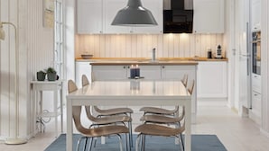 A modern kitchen with white cabinetry, a central island, and a hanging pendant light. - 5 Star Holiday Home in Vig (Vig)