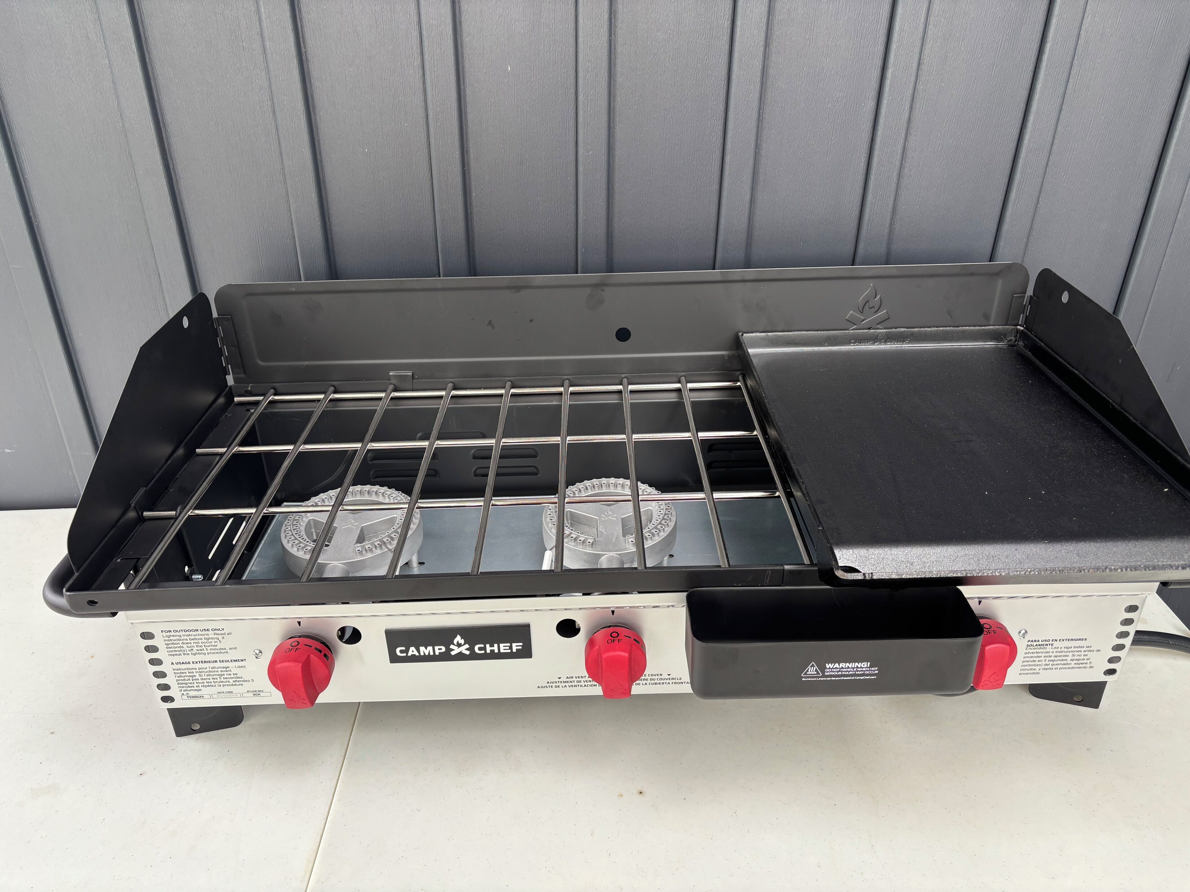 Un barbecue portatif doté d’une surface de cuisson plane et de deux boutons de réglage.
