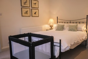 Ein Schlafzimmer mit einem Bett, einem Nachttisch, einer Lampe, einem Heizkörper und vier gerahmten Bildern an der Wand.