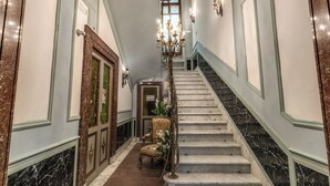 A grand staircase with a chandelier, a chair, and a door with a sign. - Venere's Villa in Rome (Roma)