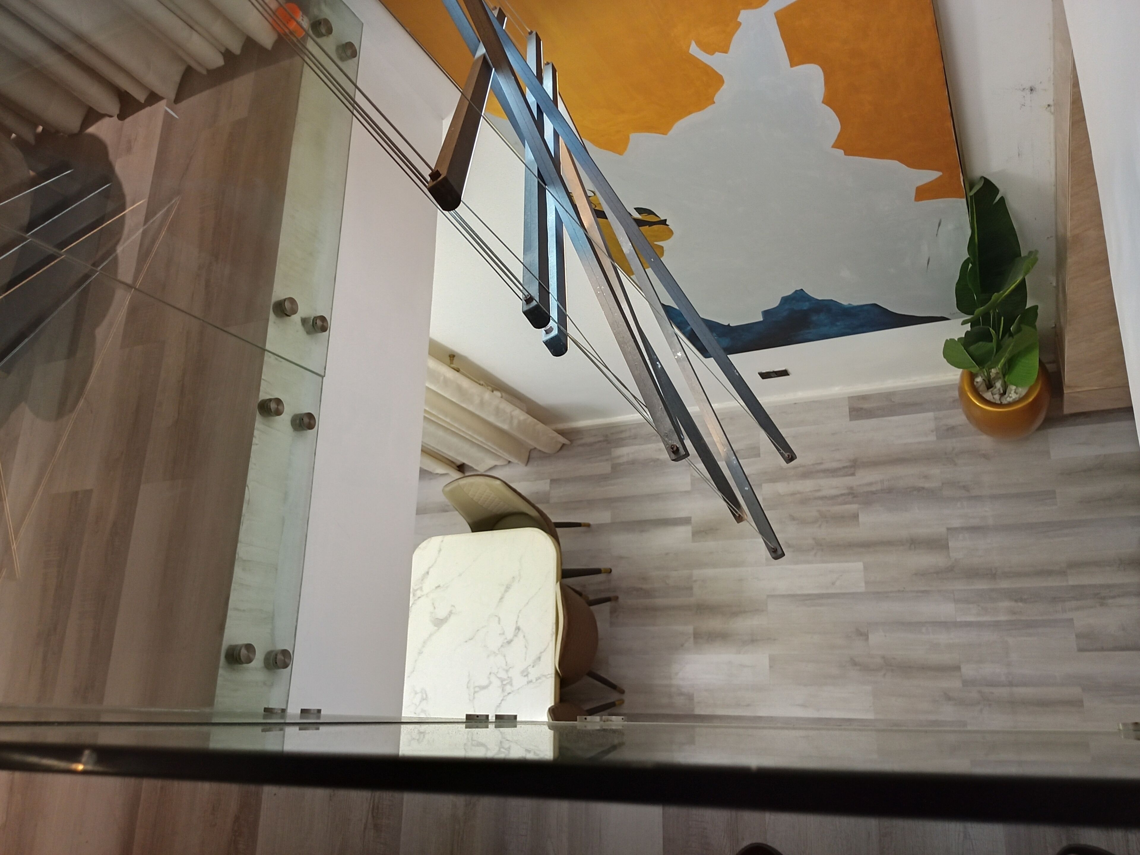 Un intérieur moderne agrémenté d’une colonne en marbre, d’une rambarde en verre et d’un mur orné d’une fresque représentant une montagne.