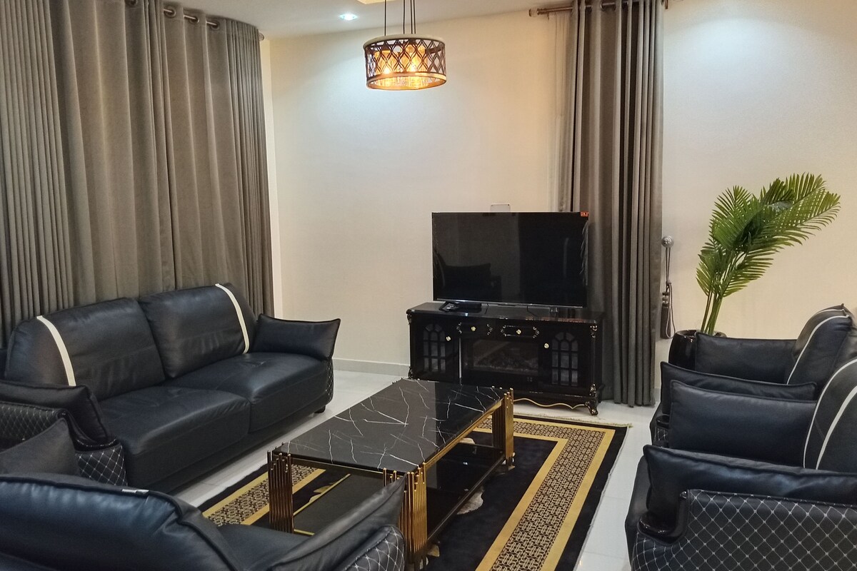 Una sala moderna con un conjunto de sofás, una mesa de centro, un televisor y una lámpara decorativa.