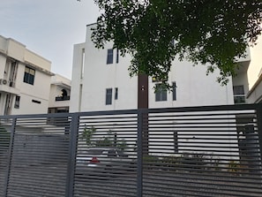 A modern building with a white facade, multiple windows, and a tree in the foreground. - Vision Luxury Apartment (Lekki)