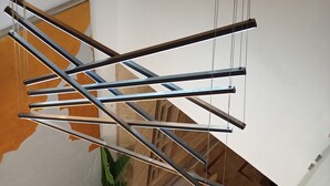 En moderne trappe med et geometrisk gelænder i metal, en potteplante og trægulv.