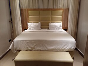 A neatly made bed with a headboard, a bedside table, and curtains. - Vision Luxury Apartment (Lekki)