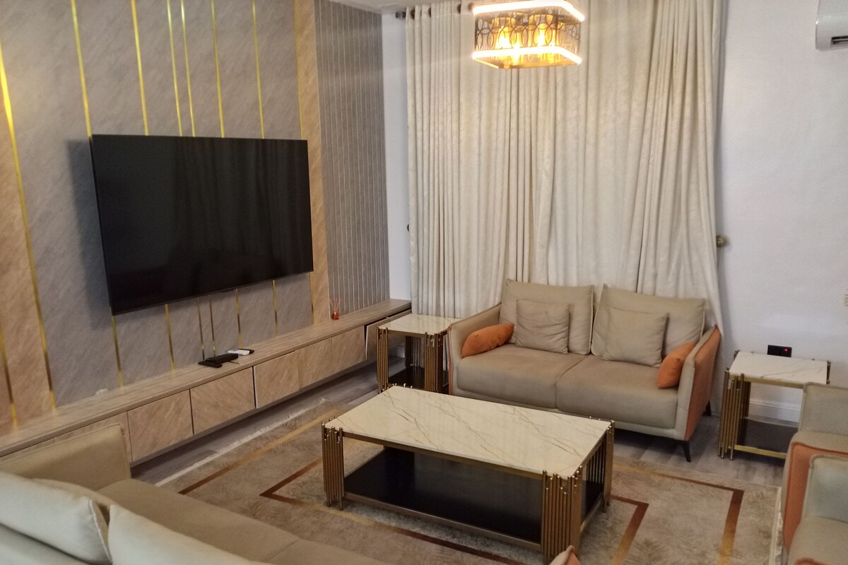 Una sala de estar moderna con una televisión de pantalla plana, un sofá, una mesa de centro y una alfombra estampada.