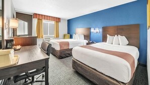 A hotel room with two beds, a desk, a chair, a desk lamp, a mirror, and a window with curtains. - City Center Inn (Newport News)