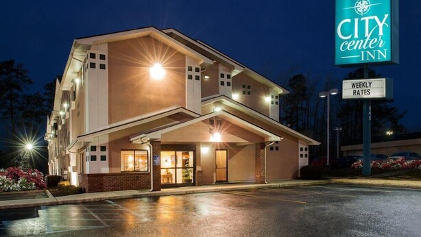 A CITY CENTER INN with a well-lit entrance, a sign indicating WEEKLY RATES, and a parking lot. - City Center Inn (Newport News)