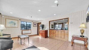 A spacious living room with a sofa, a coffee table, a fireplace, and a kitchen area with wooden cabinets. - City Center Inn (Newport News)