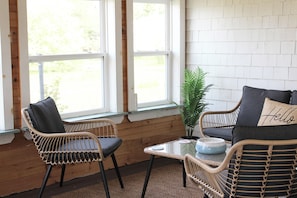 Une pièce avec des chaises en osier, une petite table et une plante en pot.