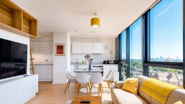 A modern apartment with a dining area, kitchen, and a large window with a city view. - Bright 1BR Home with Shared Terrace-1min to Tube (London)