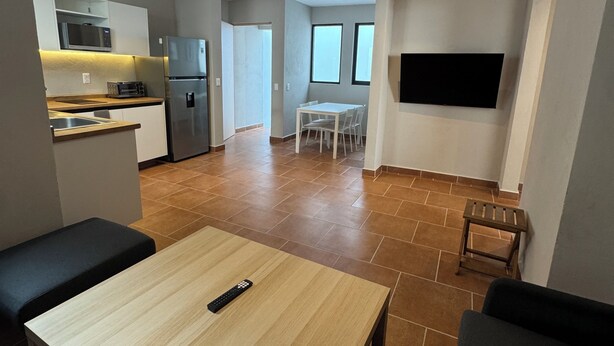 Eine moderne Wohnung mit Küche, Essbereich und einem an der Wand montierten Fernseher.