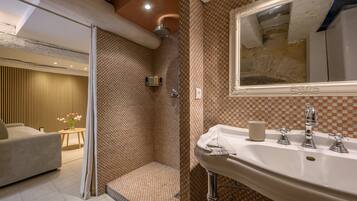 Une salle de bain avec une douche, un lavabo avec un miroir et des toilettes.