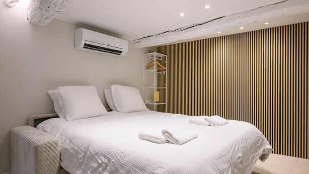 Ein modernes Schlafzimmer mit einem großen Bett, weißen Bettwäsche, einem Einbauschrank und einer Klimaanlage.