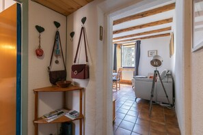 Un corridoio con uno scaffale di legno, un cesto rosso e una borsa marrone appese a dei ganci.