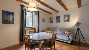 Un comedor con una mesa redonda, sillas de madera, un sofá y un trípode.