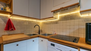 Una cocina con armarios blancos, lavavajillas, microondas y encimera de madera.