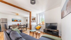 Een moderne woonkamer met een bank, televisie, eethoek en kunstwerken.