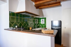 Eine Küche mit Holzarbeitsplatte, Spüle, schwarzem Kühlschrank und einer Rückwand aus grünen Fliesen.