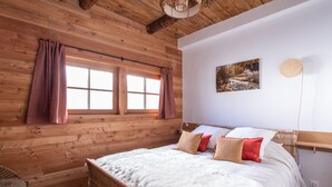 Una stanza con rivestimento in legno, un letto, una finestra con tende, una lampada a muro e un quadro.