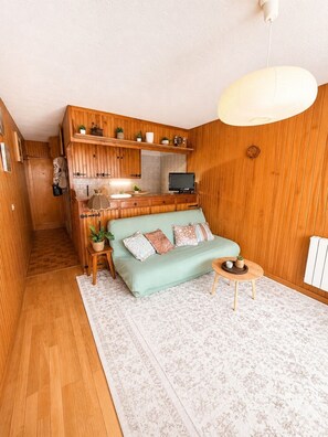 Une pièce de taille modeste, avec un canapé, une petite table, un téléviseur et des murs en bois.