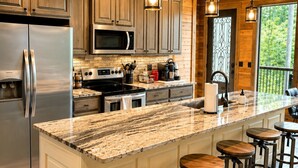 A spacious kitchen with a large island, stainless steel appliances, and wooden cabinetry. - Pine Hill Lodge - Hot Tub, Fire Pit, Sleeps 14 (Broken Bow)