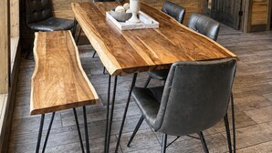 A wooden interior with a long dining table, leather chairs, and a painting of a sunset over water. - Pine Hill Lodge - Hot Tub, Fire Pit, Sleeps 14 (Broken Bow)