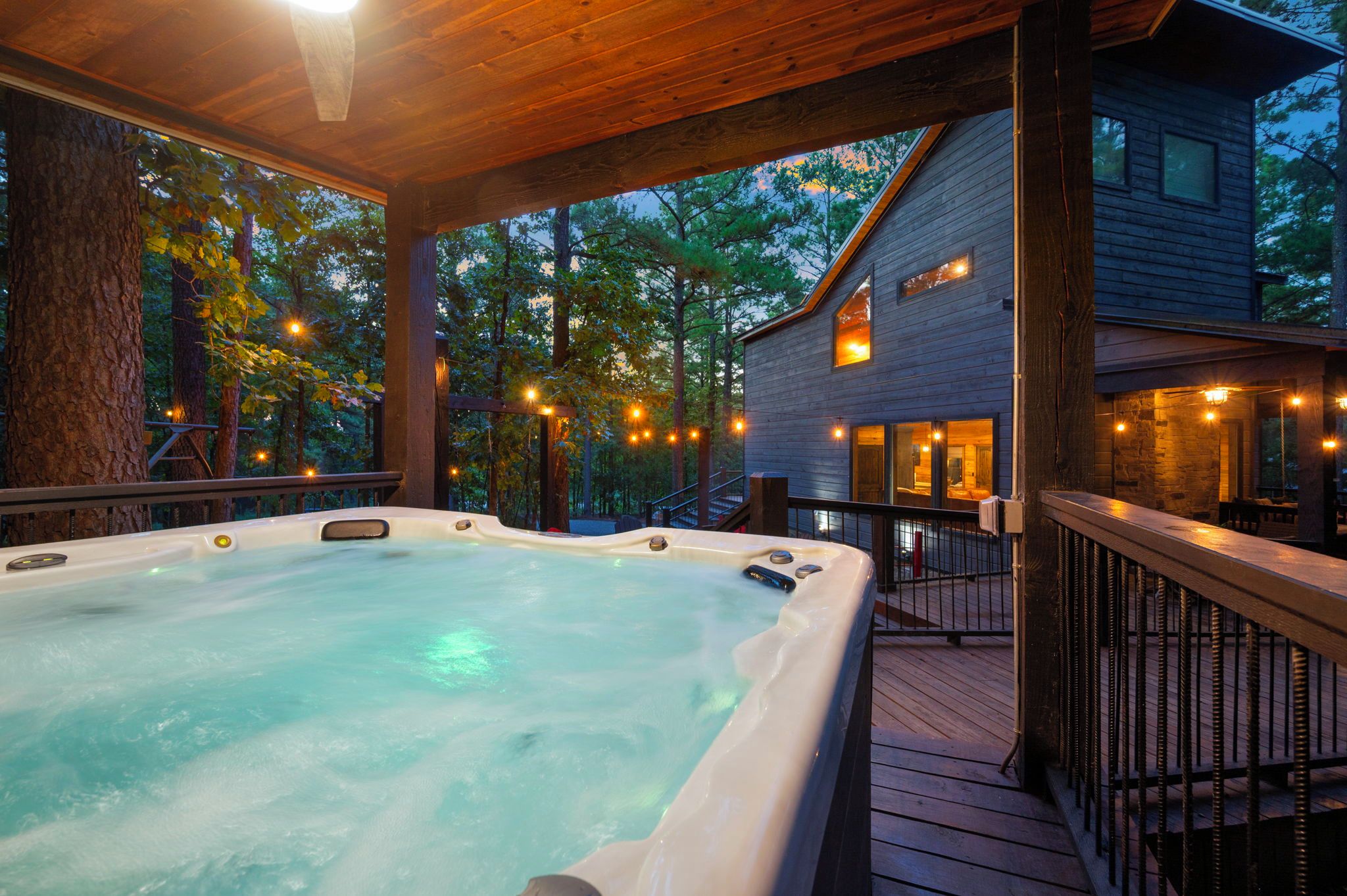 A hot tub on a wooden deck with a house in the background.