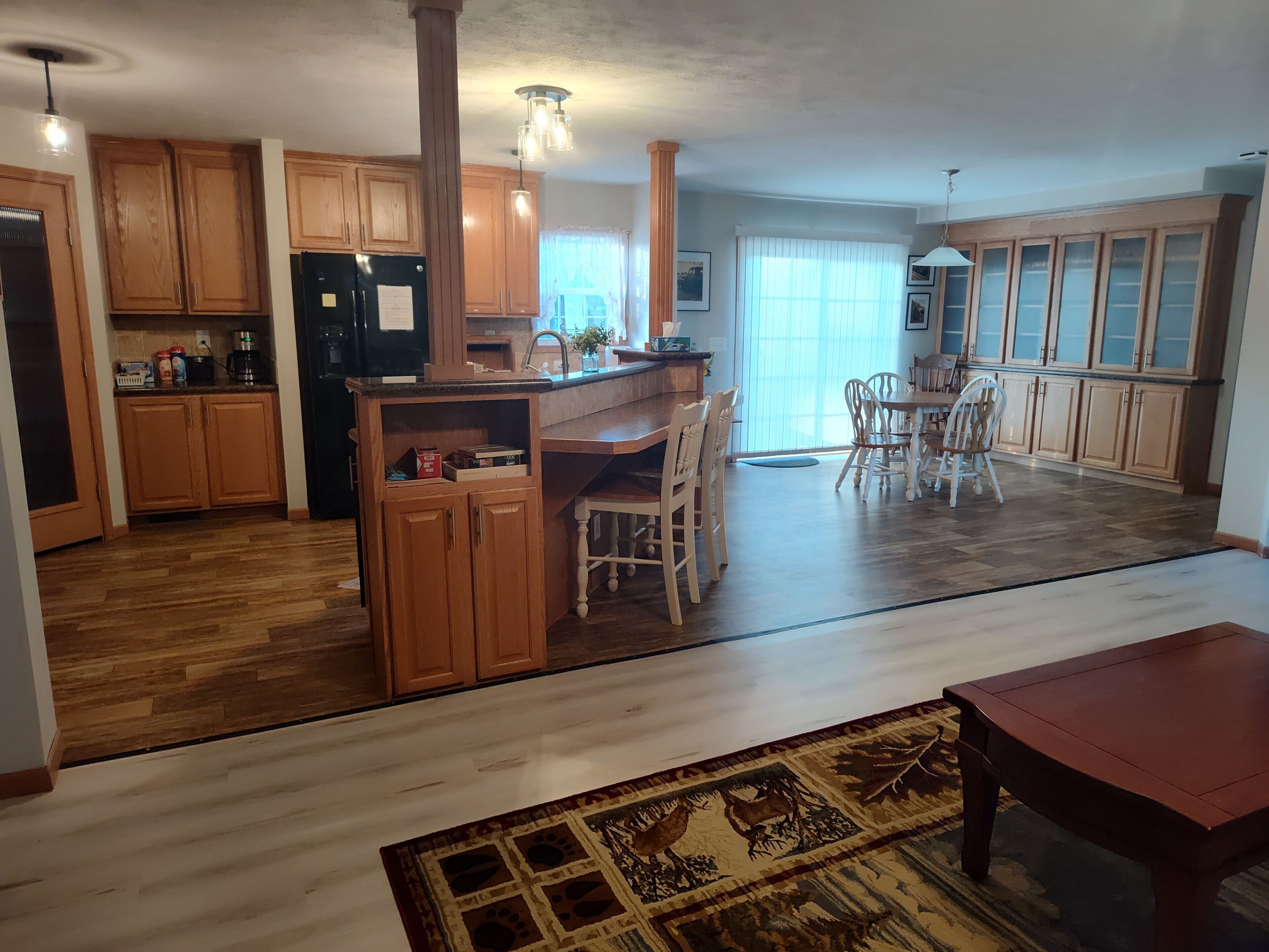 A spacious kitchen with wooden cabinets, a central island, and a dining area with chairs.