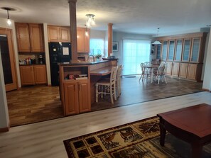 A spacious kitchen with wooden cabinets, a central island, and a dining area with chairs.