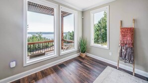 A room with large windows, a wooden floor, and a view of a lake. - Enjoy stunning Pickwick Lake views and water access from Aqua Vista Pickwick! (Hardin County)