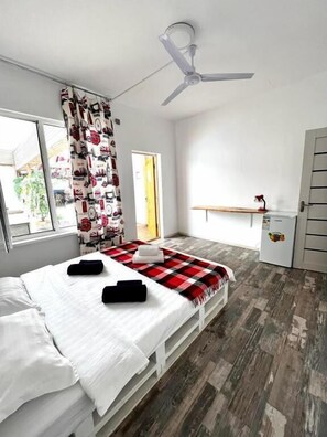 A bedroom with a bed, a ceiling fan, a window with curtains, and a door. - Hotel7 (Kapchagay)