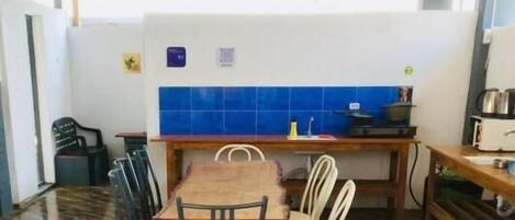 A dining area with a wooden table and chairs, a tiled backsplash, and a variety of flags hanging from the ceiling.