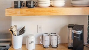 A kitchen with wooden shelves, a coffee maker, and kitchen utensils. - Nestled on New Bern - Bright Bungalow Downtown (Raleigh)