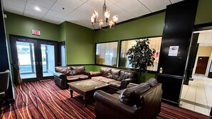A lobby with a red carpet, leather couches, a chandelier, and an exit sign.